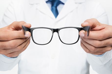 Optometrista sosteniendo unas gafas de pasta negra